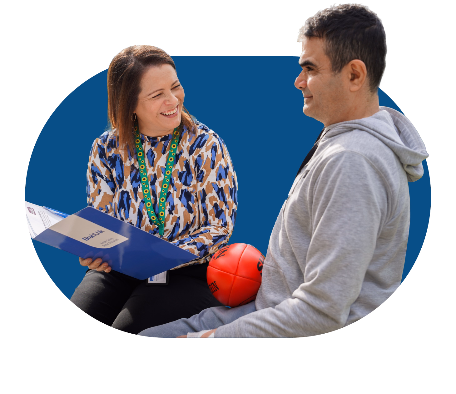 BrainLink NDIS coordinator shares support program info with participant living with an acquired brain injury at a community event.