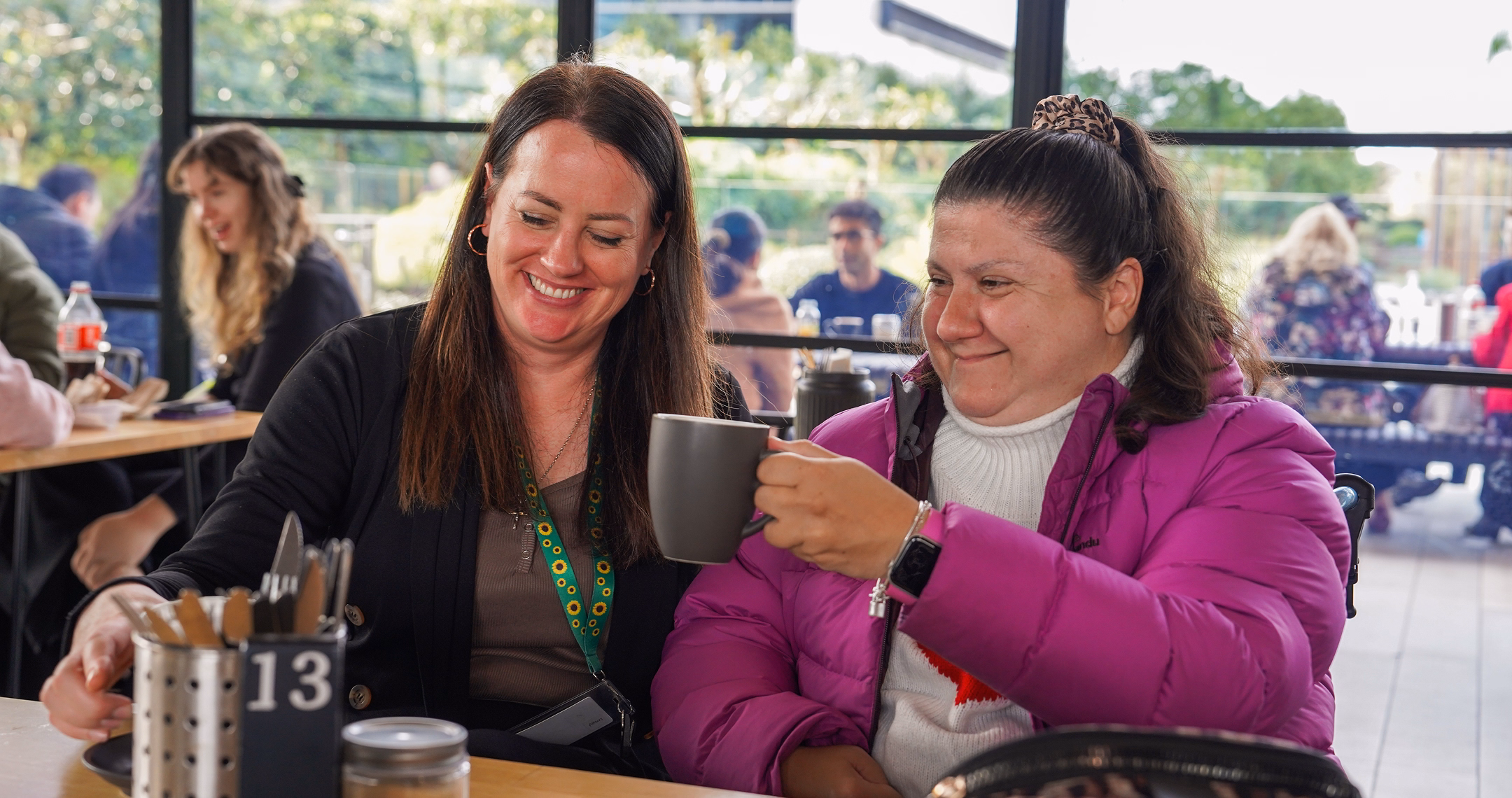 BrainLink NDIS coordinator sharing a drink indoors with support program participant who lives with an acquired brain injury.